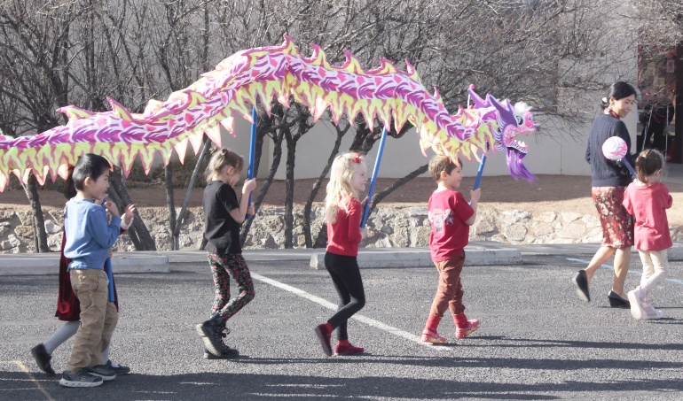 A group of kids walking with a dragon shaped object

AI-generated content may be incorrect.